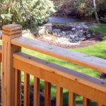 A Western Red Cedar railing overlooks a backyard with a pond.