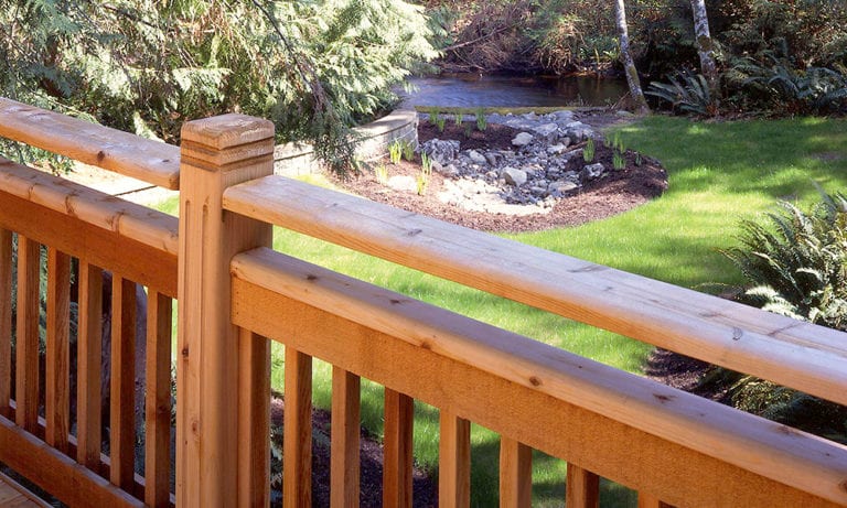 A Western Red Cedar railing overlooks a backyard with a pond.