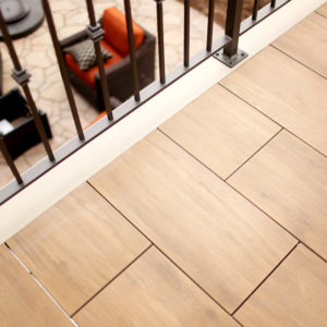 This image depicts a close-up of the wood effect tiles on an elevated deck overlooking the paved backyard.
