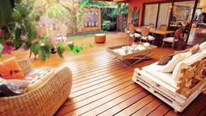 This image depicts an outdoor decking area with a sofa, a chair, a coffee table and a dining table.