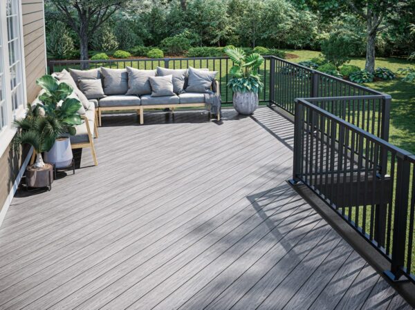 A light gray deck with a comfortable seating area has various green plants.