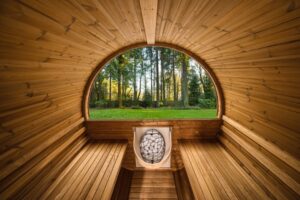 n the picture above there is a wooded sauna overlooking a green yard and tree line.