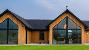 This wood home has black trim and large windows. Green grass is located in front of the home. 