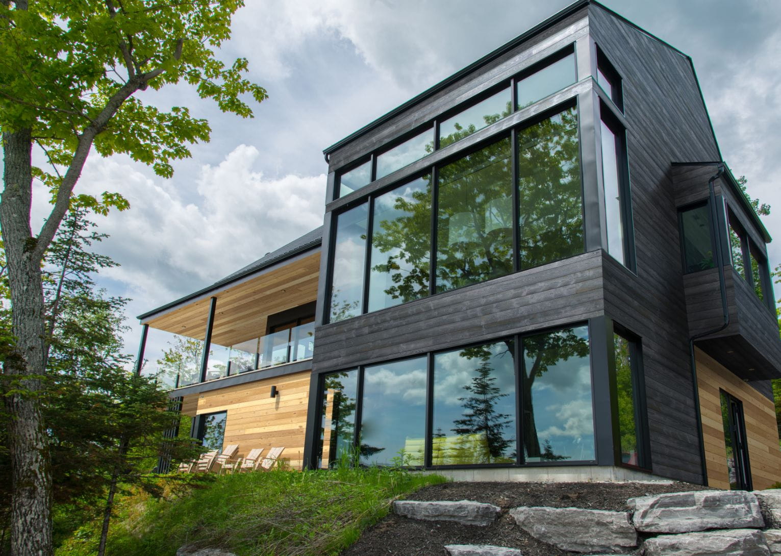 This image depicts a large house with black wooden siding.