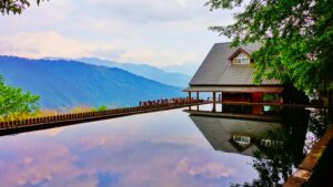 In the image above, there is a house on the right with an infinity pool and both the house and the pool overlook a mountain range. 