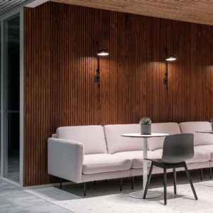 This picture depicts an eating area with pine paneling incorporated throughout the space. The round table has a chair on one side and a sofa on the other. A small potted plant is placed on the table.