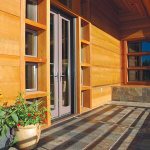 This picture depicts a home with cedar siding. There is a flower pot next to the front door.