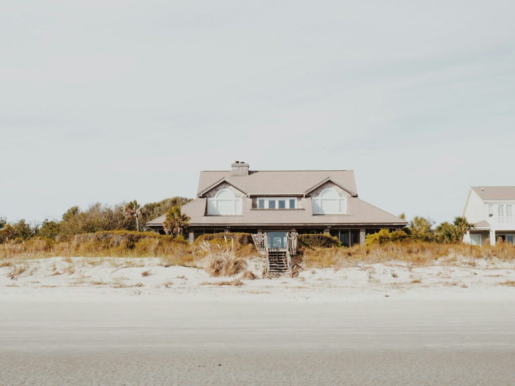 A coastal home with a tan roof and steps going directly onto the beach.