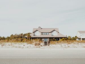 A coastal home with a tan roof and steps going directly onto the beach.
