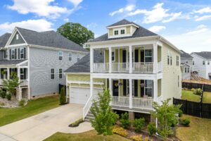 A two-story green house with white trim has a white vinyl railing system on the first- and second-story porch.