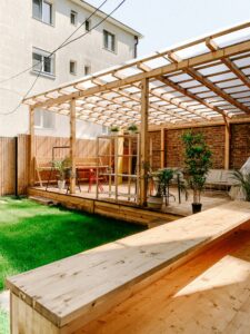 This image depicts a deck area with a built-in bench. One part of the deck is covered and the other is not.
